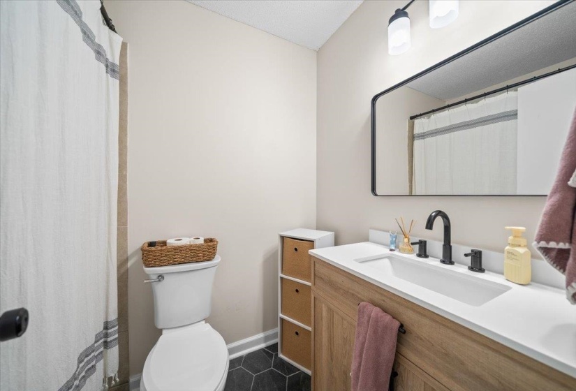 Bathroom with a wood-finish vanity, integrated sink, and matte black fixtures