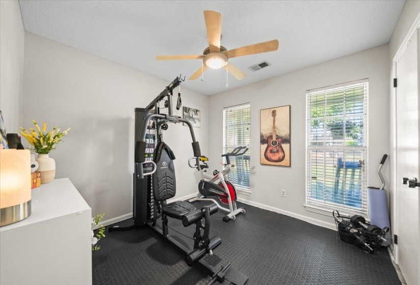 Interior room featuring textured rubber flooring, light gray walls, and two large windows with horizontal blinds