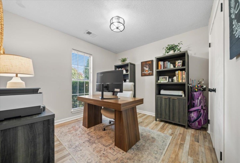 Bright interior room with wood-finish flooring and a central window with blinds