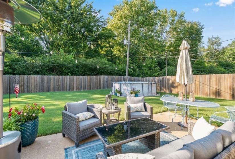 Expansive backyard featuring a concrete patio, a privacy fence, and mature trees