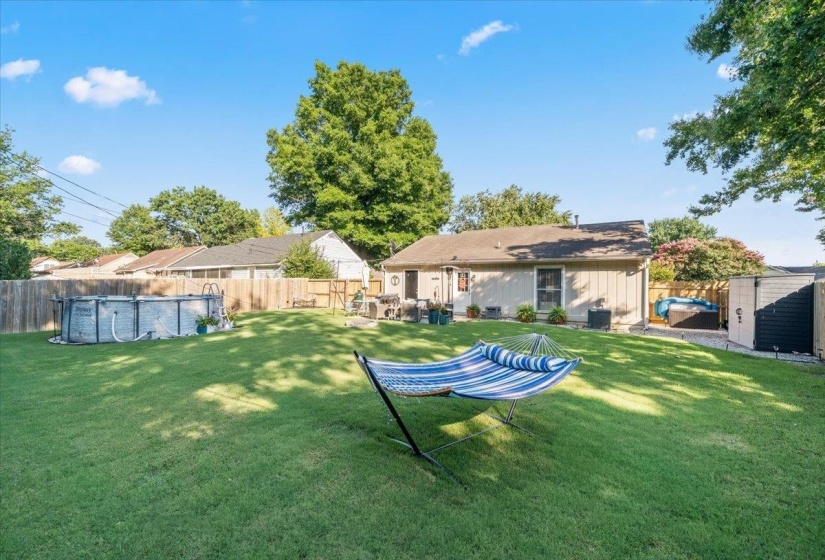Expansive backyard featuring a large above-ground pool, a hot tub, and two outdoor storage sheds