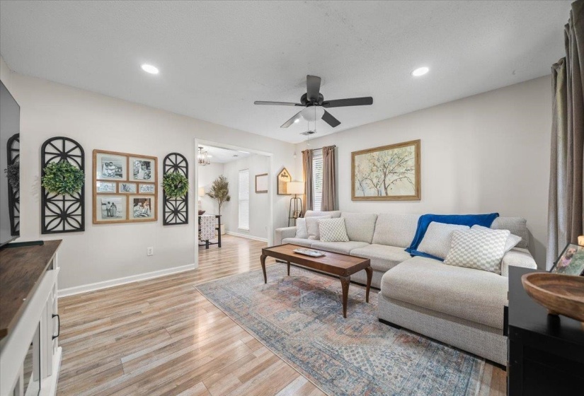 Spacious living area featuring light wood-finish flooring, recessed lighting, a ceiling fan, and a wide entryway to an additional room