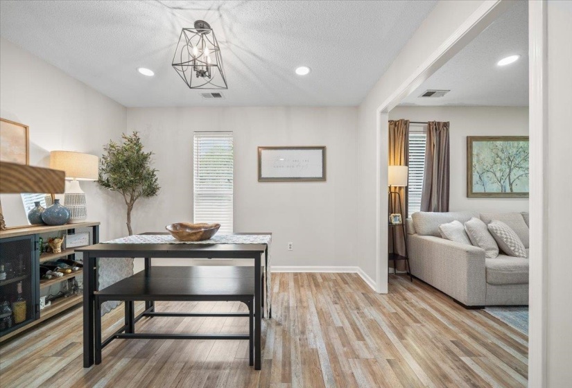 Spacious open-concept living area featuring wood-finish flooring, recessed lighting, and a contemporary geometric light fixture