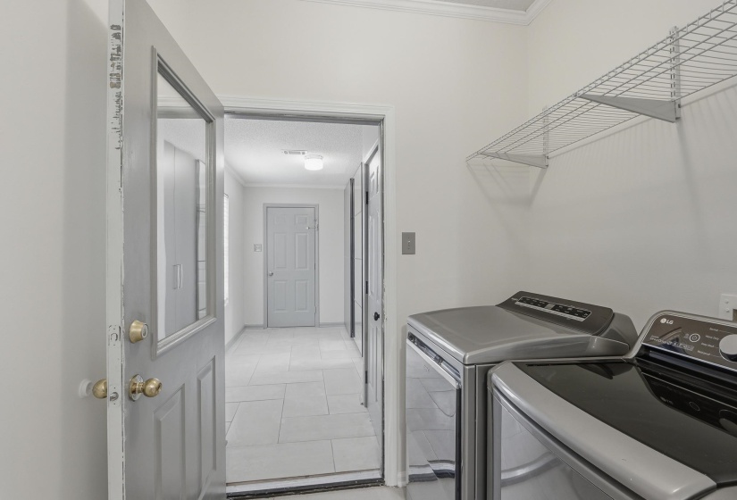 Dedicated laundry area featuring a washer and dryer, an overhead wire shelving unit, and light tile flooring