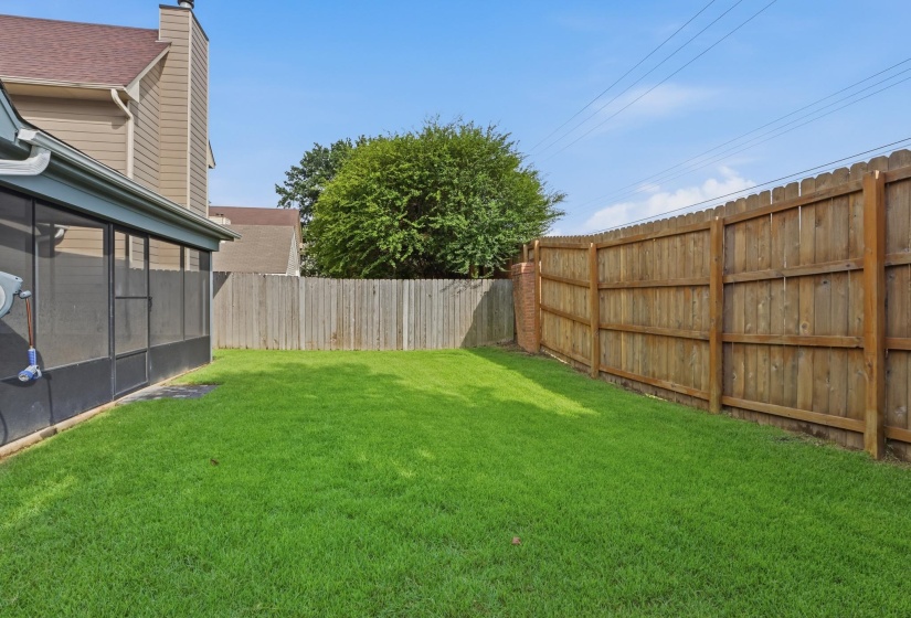 Expansive green lawn with a full privacy fence