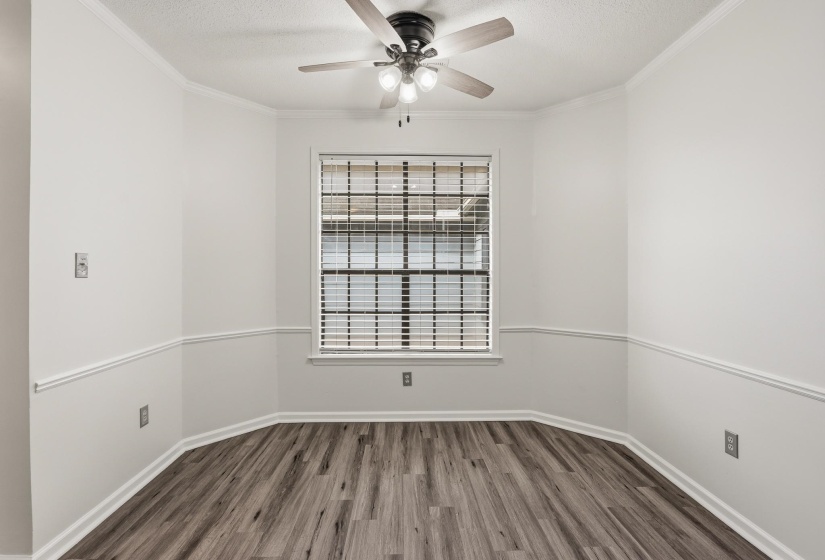 Interior space featuring wood-finish flooring, white walls with chair rail molding, and a window with horizontal blinds