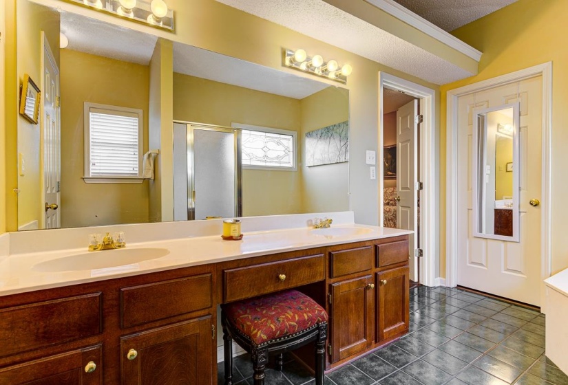 Double vanity with integrated sinks, white countertop, and wood-finish cabinetry