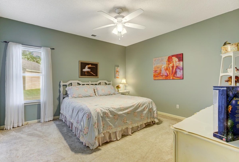 Carpeted bedroom featuring a ceiling fan with light, a window with blinds, and painted walls