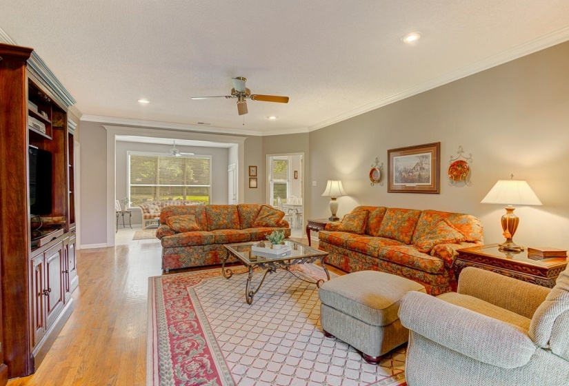 Spacious living area featuring wood-finish flooring, recessed lighting, and crown molding