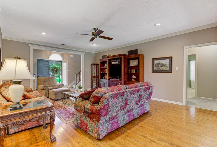 Living area featuring wood-finish flooring, ceiling fan, crown molding, and recessed lighting