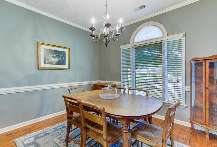 Formal dining area featuring hardwood flooring, crown molding, and chair rail detailing