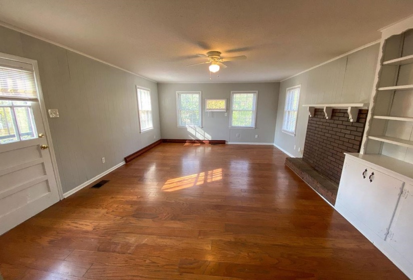 Spacious room featuring wood-finish flooring, light grey walls, and a ceiling fan with integrated lighting