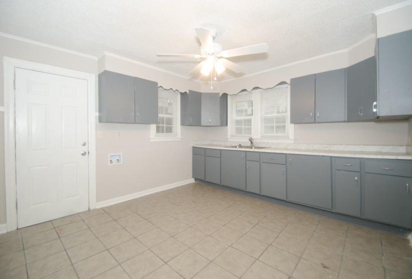 Kitchen featuring gray cabinetry, light-toned countertops, a ceiling fan with integrated lighting, a stainless steel sink, and tile flooring