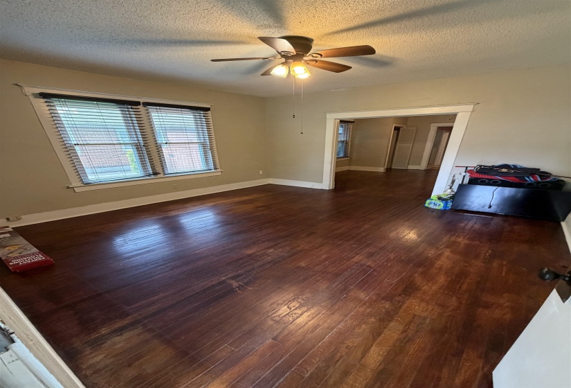 Spacious room featuring wood-finish flooring, neutral-toned walls, and a ceiling fan with integrated lighting