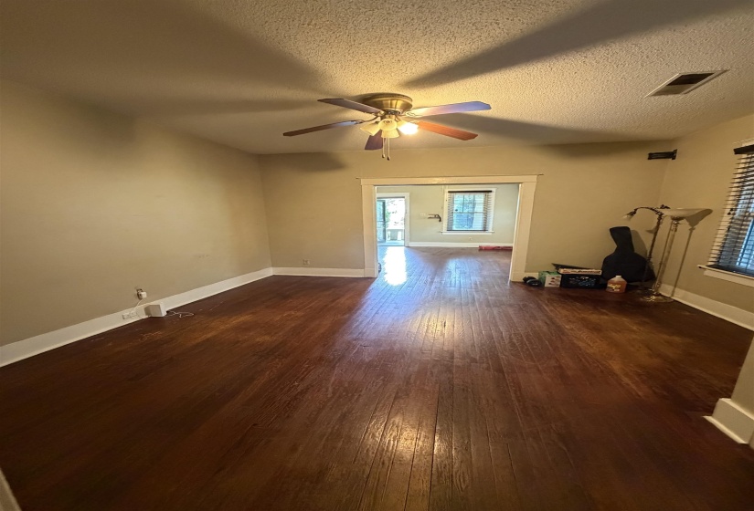 Hardwood flooring extends throughout this room, complemented by a ceiling fan with integrated lighting