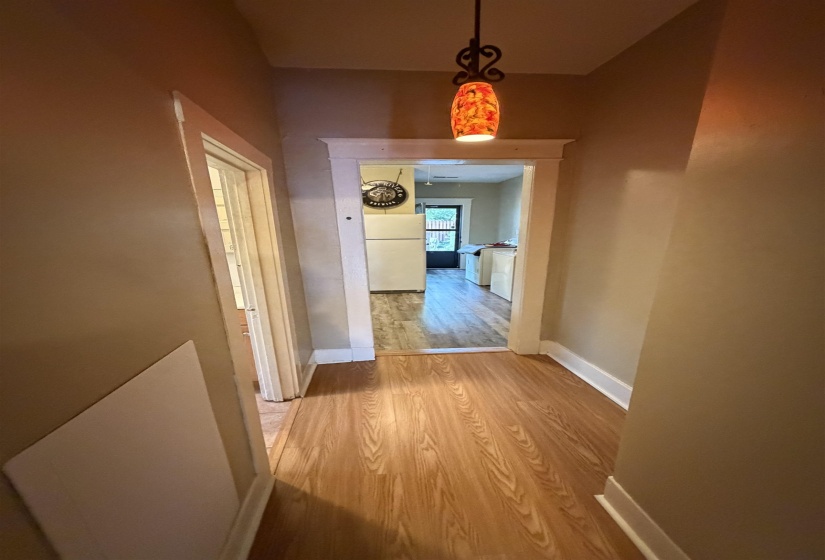 Hallway featuring wood-finish flooring, white baseboards, and a decorative pendant light fixture
