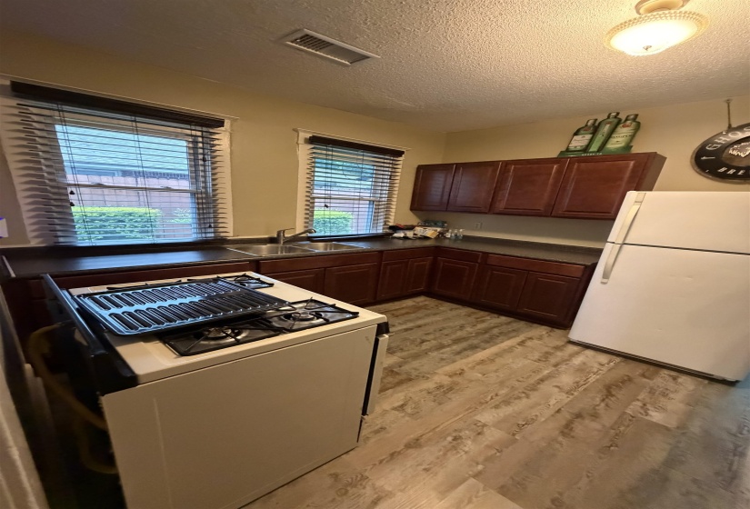 Kitchen featuring dark wood-finish cabinetry, a double basin sink, and wood-finish flooring