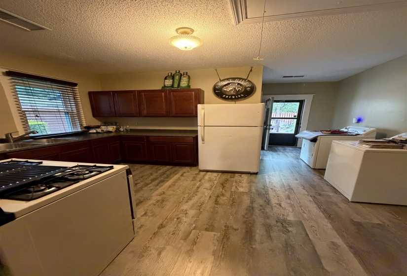 Functional kitchen featuring wood-finish flooring, dark wood cabinetry, a stainless steel double basin sink, and a gas range