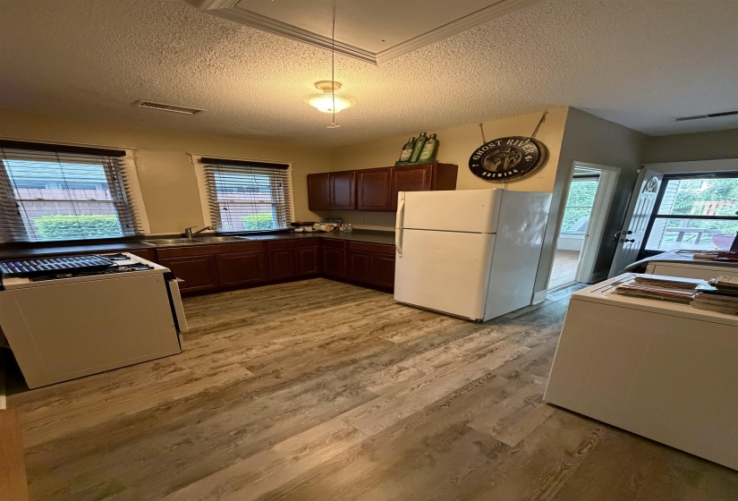 Kitchen featuring wood-finish flooring, dark wood cabinetry, a double basin sink, and pendant lighting