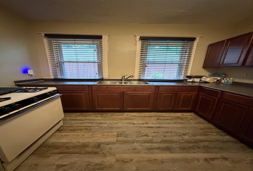 Kitchen featuring wood-finish flooring, cherry-toned cabinetry, and dark countertops