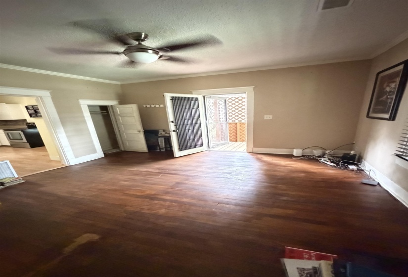 Spacious room with wood-finish flooring, featuring a ceiling fan with integrated lighting
