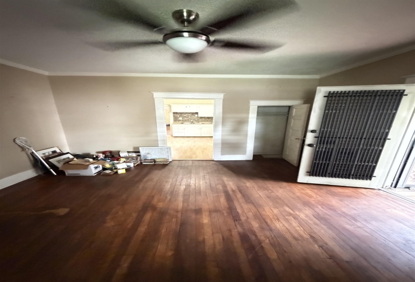 Hardwood flooring throughout, featuring a ceiling fan with integrated lighting, crown molding, and white trim work