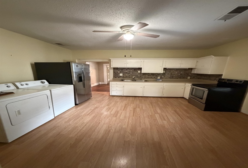 Kitchen area featuring wood-finish flooring, white cabinetry, and a tile backsplash