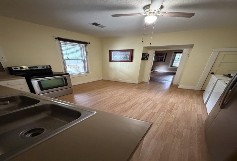 Kitchen area featuring wood-finish flooring, stainless steel range, double basin sink, and a ceiling fan with light fixture