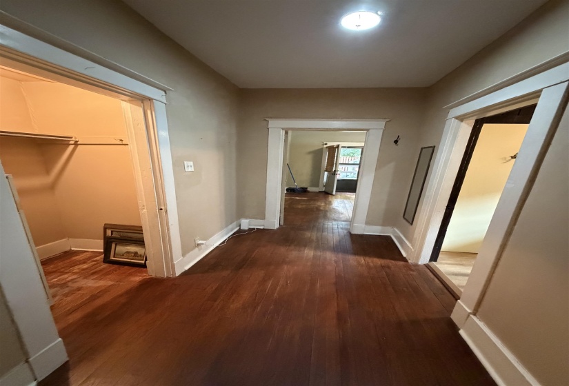 Hallway featuring wood-finish flooring, light-toned wall paint, and white trim