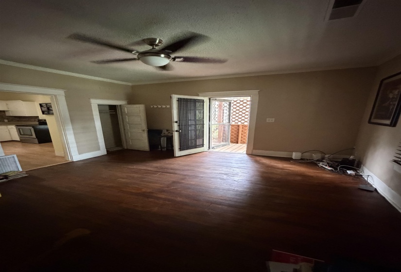 Living area featuring dark wood-finish flooring, a ceiling fan with integrated lighting, and direct access to an outdoor screened porch