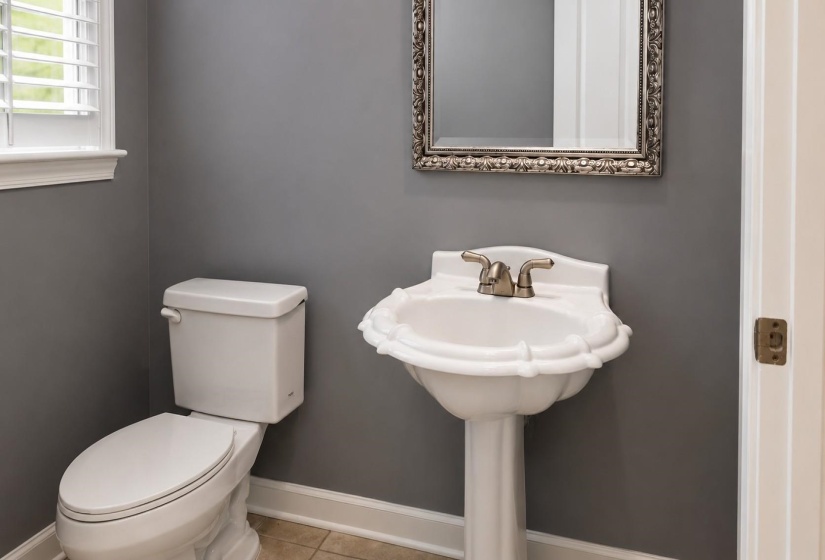 Pedestal sink with brass-finish faucet, framed mirror, and window with plantation shutters