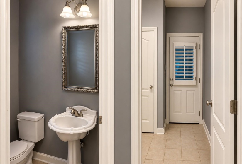 Powder room featuring a pedestal sink, framed mirror, and a two-bulb vanity light