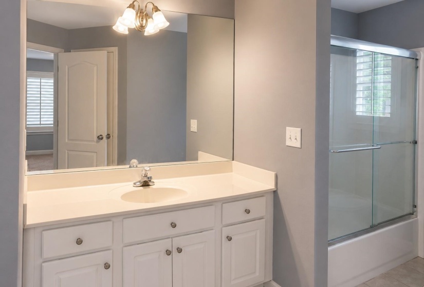 Bathroom featuring a vanity with an integrated sink, white cabinetry, and a full-width mirror