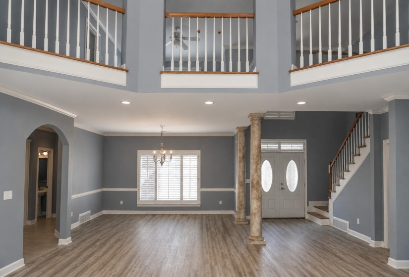 Two-story foyer featuring columns, a double-door entry with decorative glass, and a grand staircase with wood handrails