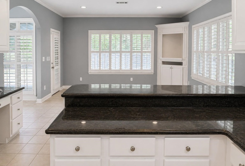 Kitchen island featuring a two-tier countertop with dark stone surfacing and white cabinetry