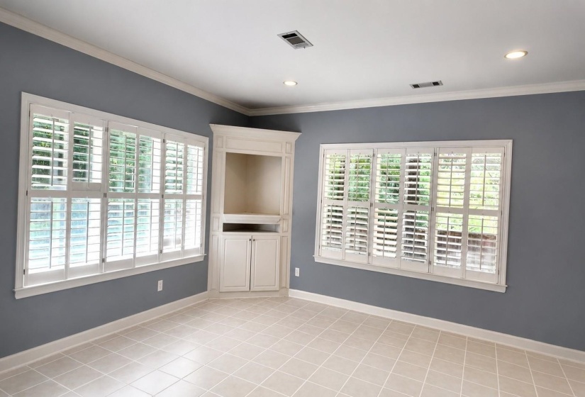 Neutral tile flooring complemented by white baseboards and crown molding