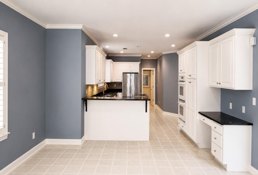 Spacious kitchen and dining area featuring light tile flooring, white cabinetry, dark countertops, recessed lighting, and built-in stainless steel appliances