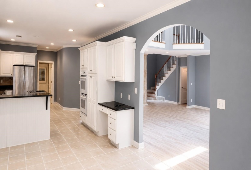 Kitchen and living area featuring a spacious island, white cabinetry, dark countertops, and stainless steel appliances