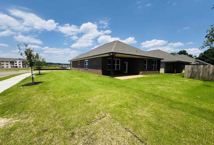 Rear view of house featuring a lawn and brick siding