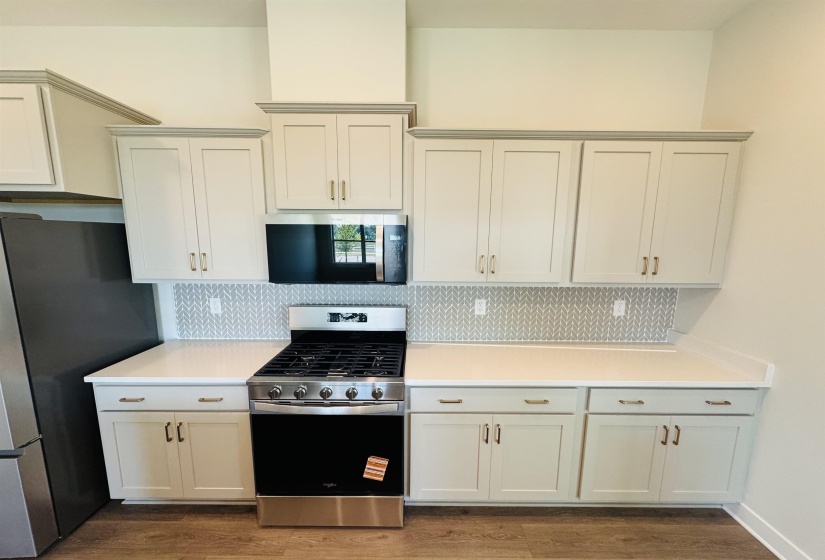 Kitchen featuring appliances with stainless steel finishes, decorative backsplash, and dark wood-type flooring