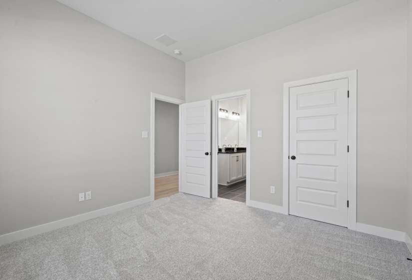 Unfurnished bedroom with light colored carpet, a closet, and connected bathroom