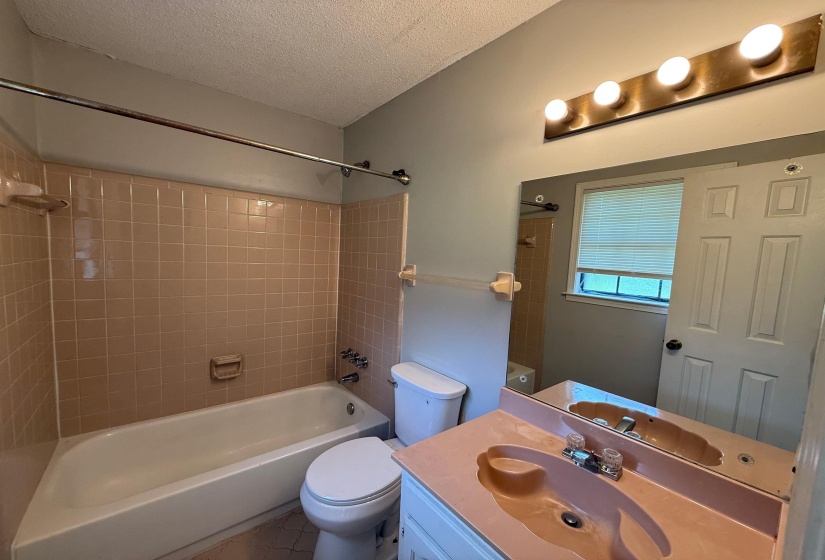 Bathroom featuring a tub/shower combination with tile surround, a single vanity with an integrated sink, and a mirrored wall