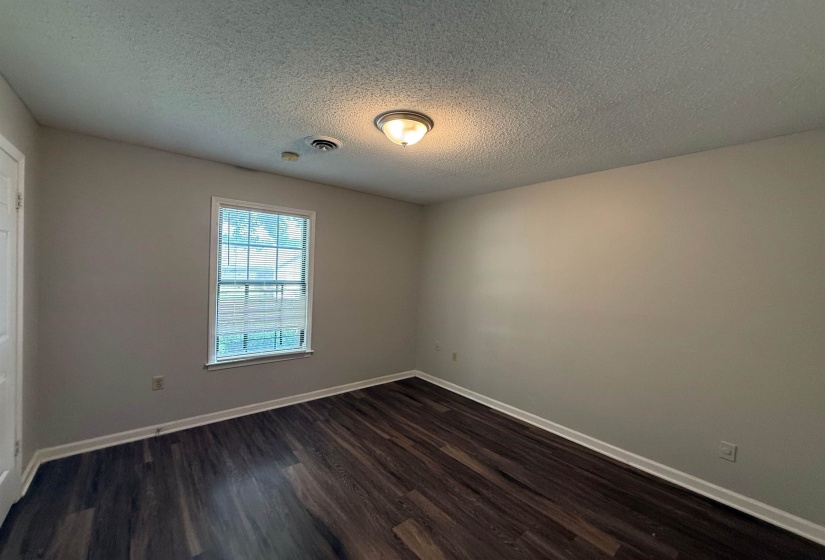Interior room featuring wood-finish flooring, light-toned walls, and a single window with blinds