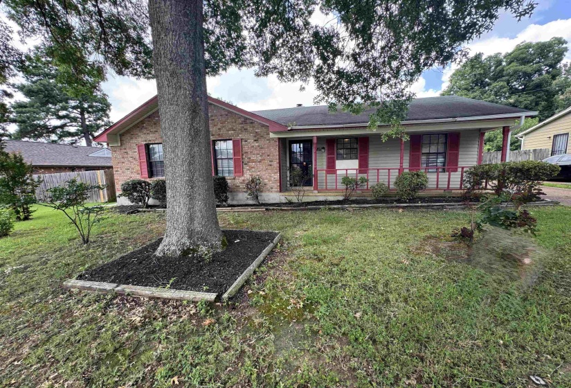 Brick and siding exterior featuring red shutters and a covered front porch with a railing