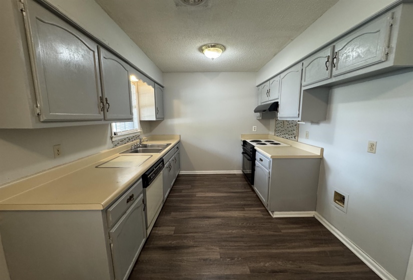 Galley kitchen featuring wood-finish flooring, light-colored countertops, gray cabinetry, and a double-basin stainless steel sink