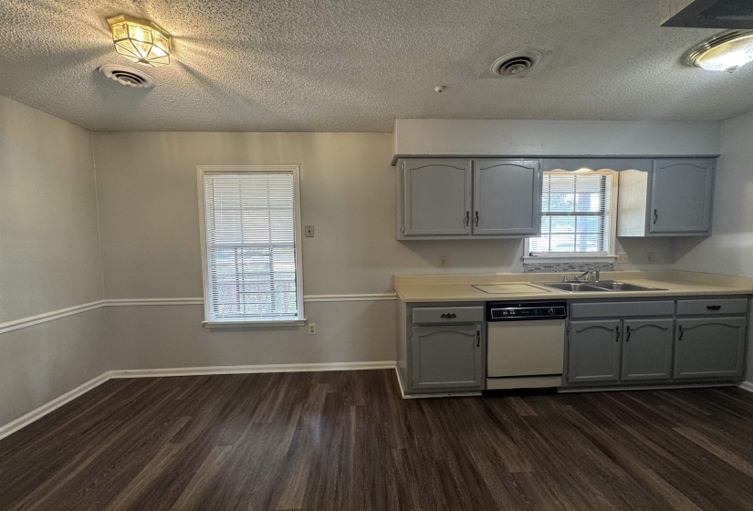 Kitchen area featuring wood-finish flooring, gray cabinetry, a double basin sink, and a built-in dishwasher
