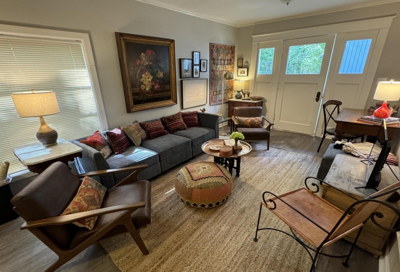 Living area featuring wood-finish flooring, a window with horizontal blinds, and a built-in trim package