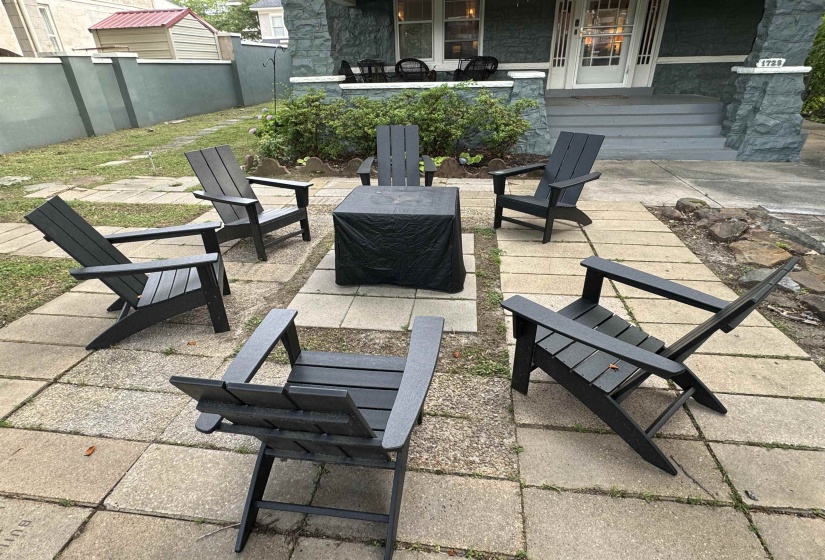 Paver patio area featuring a stone exterior home with a covered front porch and mature landscaping