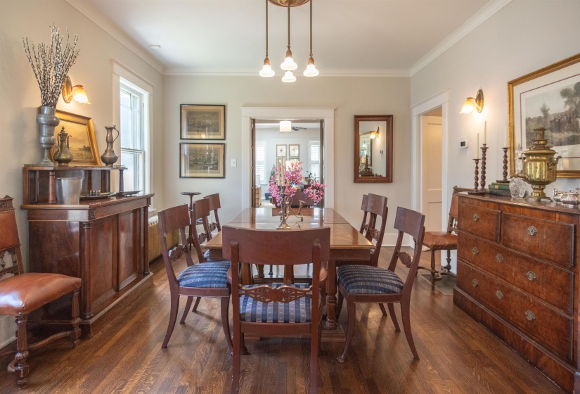 Dining area featuring wood-finish flooring, crown molding, wall sconces, and a multi-bulb chandelier