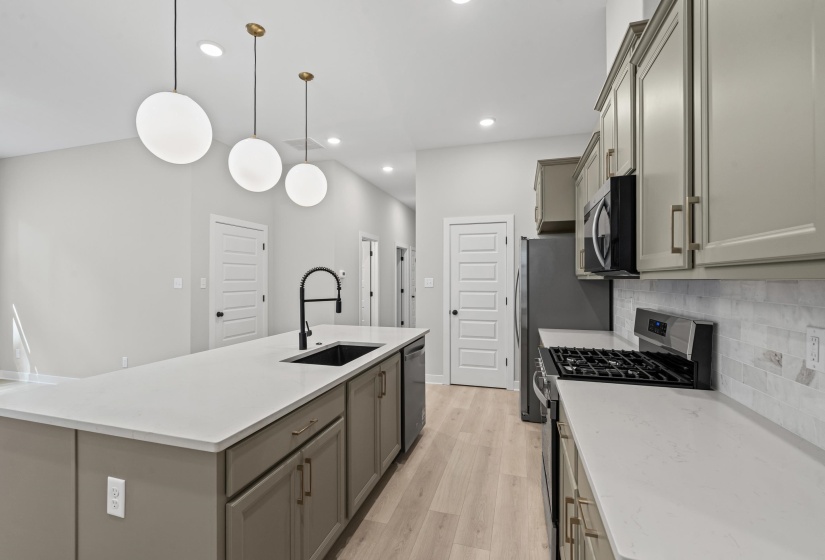 Kitchen featuring appliances with stainless steel finishes, gray cabinetry, light wood-style floors, a kitchen island with sink, and hanging light fixtures